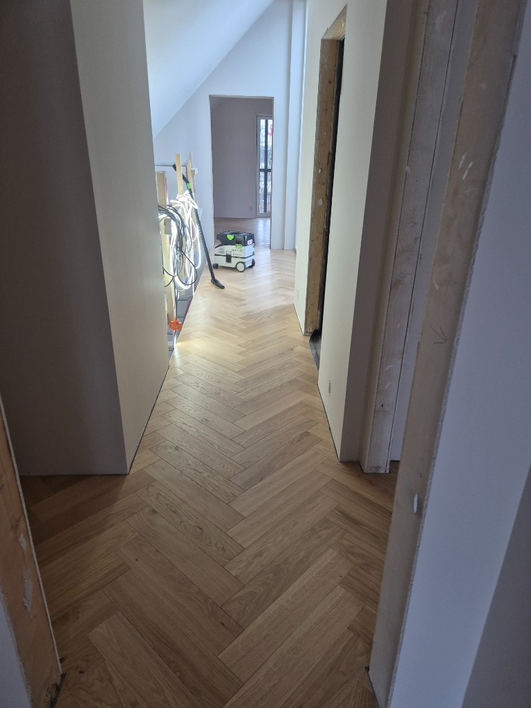 Nylagt fiskebensmønstret parkett i lys eik i moderne gang.